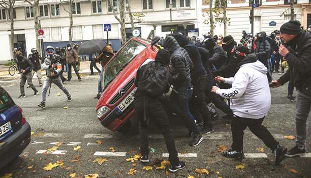 Protesters overturn a car near Parisu2019s Place du2019Italie during a u2018yellow vestu2019 demonstration marking the first anniversary of the movement.