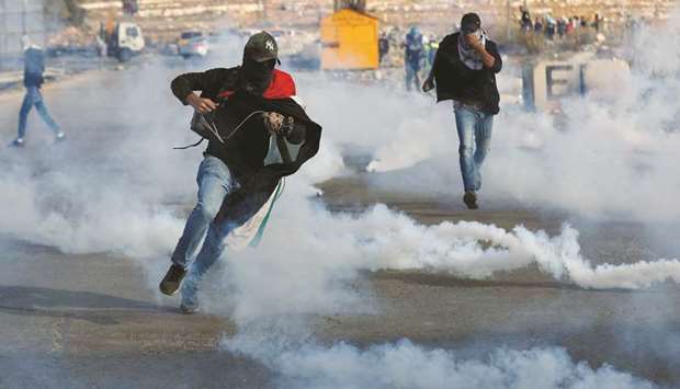 Palestinian demonstrators run away from tear gas fired by security forces during an anti-Israel protest near the settlement of Beit El in the occupied West Bank, yesterday.