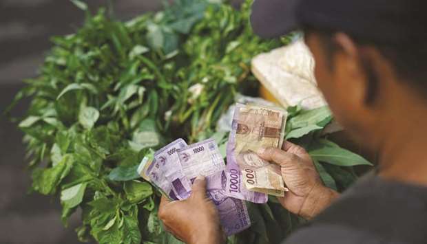 A vegetable vendor counts Indonesian rupiah banknotes in Jakarta (file). The currency is attractive due to the u201cmarket friendlyu201d make-up of the new Indonesia cabinet, which should be supportive for Indonesian assets, according to Pimco.