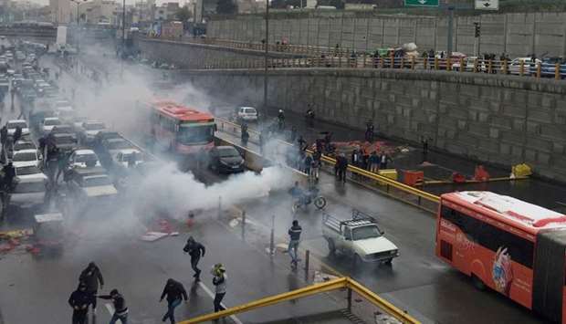 Riot police tries to disperse people on Saturday as they protest on a highway against increased gas price in Tehran