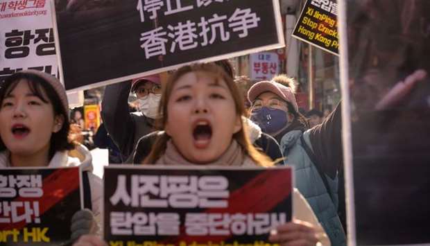 Student groups supporting the Hong Kong pro-democracy protests hold placards and shout slogans as they march during a show of solidarity, in the popular Myeongdong tourist shopping area of Seoul