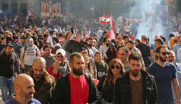 Smoke rises as demonstrators walk during the ongoing anti-government protest, in Beirut