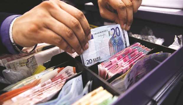 An employee places a bundle of twenty euro banknotes into a cashieru2019s tray in this arranged photograph taken inside a Travelex store in London (file).