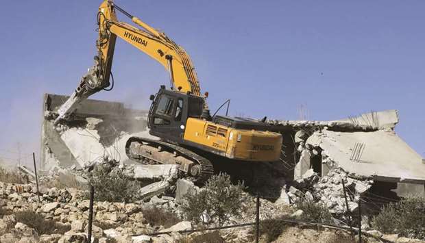 An Israeli bulldozer demolishes Palestinian houses near Al-Arub camp, on the outskirts of the West Bank town of Hebron, yesterday, as they were reportedly built without authorisation.