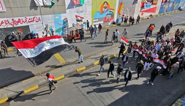Iraqi youths waving national flags march through Tahrir Square in the Iraqi capital Baghdad as anti-government protests continued across the country