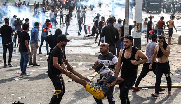 Iraqi protesters carry away an injured comrade amid clashes with riot police during a demonstration against state corruption and poor services, at Baghdad's Tahrir Square