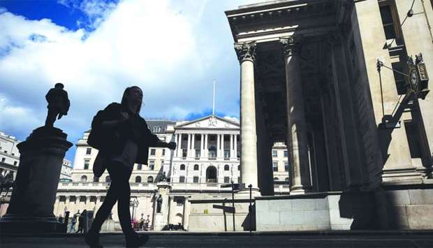 A pedestrian walks past the Bank of England in the City of London