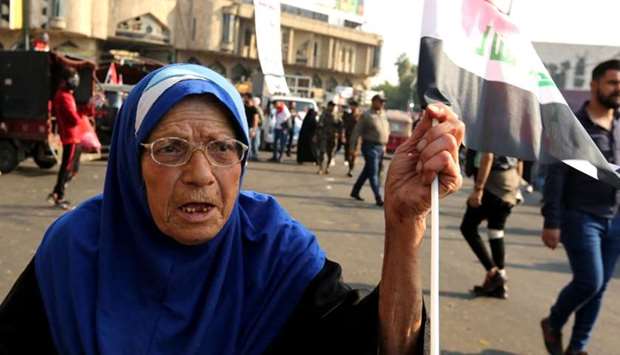 An elderly Iraqi woman waves a national flag in the capital Baghdad's Tahrir square during ongoing anti-government demonstrations