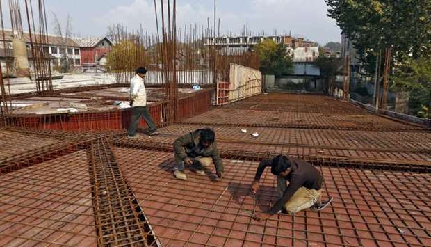 Migrant workers fasten iron rods together at the construction site of a parking lot in Srinagar.