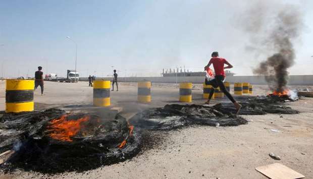 Iraqi protesters burn tires as they block the entrance of Umm Qasr Port south of Basra, Iraq
