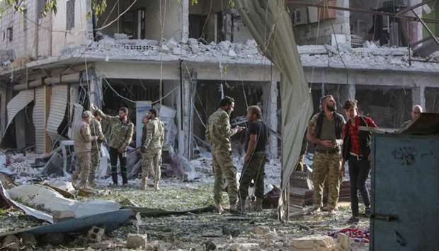 Turkey-backed Syrian fighters inspect the site of a car bomb explosion in the northern Syrian Kurdish town of Tal Abyad, on the border with Turkey