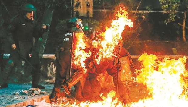 Riot police are hit by a petrol bomb during clashes with demonstrators in Santiago on Friday.