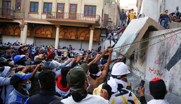 Iraqi demonstrators try to pull down concrete walls during the ongoing anti-government protests in Baghdad