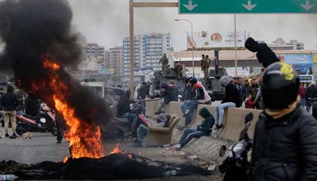 Lebanese anti-government protesters burn tyres to block the road leading to the southern entrance of the northern port city of Tripoli