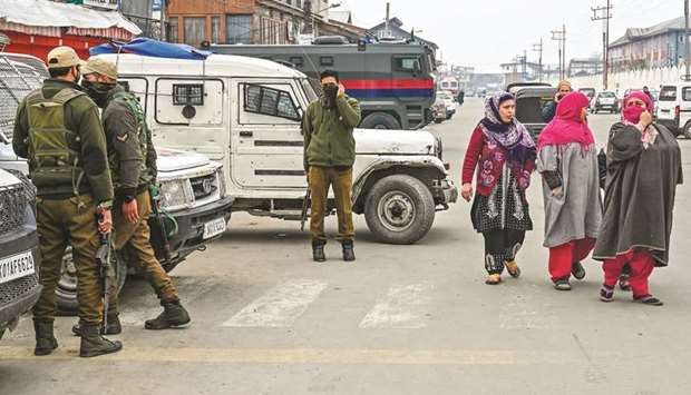 Security personnel stand near the site of a grenade blast as residents walk on a roadside at a marketplace outside the campus of Kashmiru2019s main university in Srinagar yesterday.