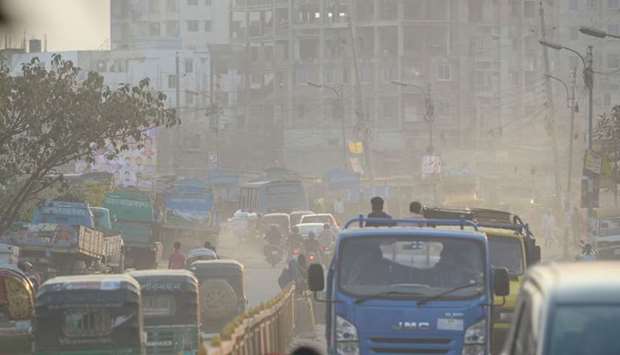 Motorists drive on a road under heavy smog conditions in Dhaka yesterday.