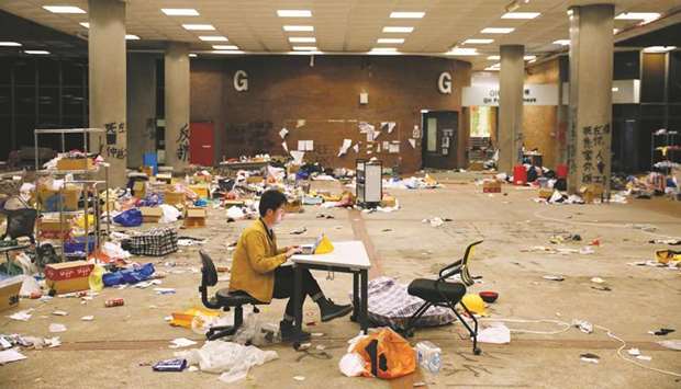A journalist works on his laptop amid items left behind by protestors in Hong Kong Polytechnic University (PolyU) in Hong Kong.