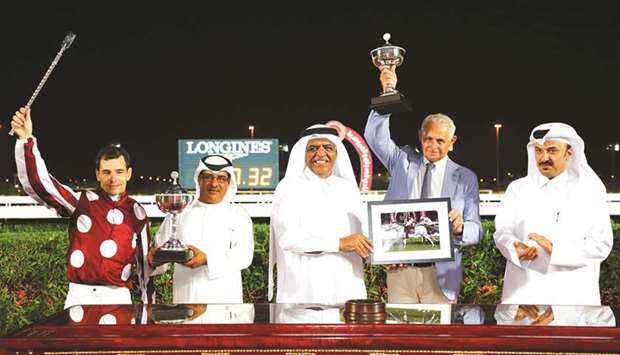 Mohamed bin Abdullah al-Malki (centre) and QREC Board member Ahmed Abdulmalik (right) with the winners of the Purebred Arabian Guineas after Umm Qarnu2019s Marid won the 1600m race yesterday. PICTURES: Juhaim