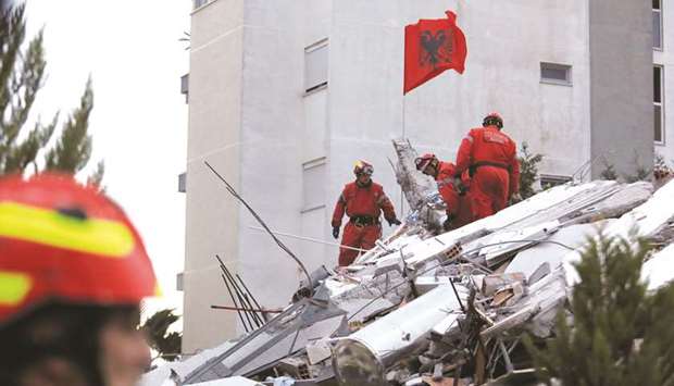 Emergency personnel put an Albanian flag on top of rubble, on the occasion of the Albanian Independence Day, during a search yesterday for survivors in a collapsed building in Durres.