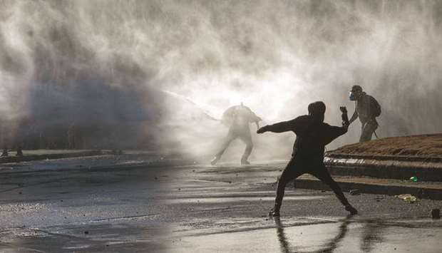 Demonstrators are hit by water cannon during a protest in Santiago on Wednesday.
