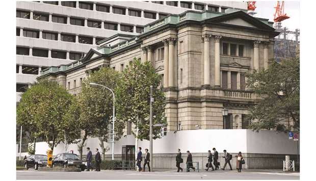 Pedestrians cross a road in front of the Bank of Japan headquarters in Tokyo. Slowing global growth, a higher sales tax and a string of natural disasters are giving BoJ policymakers plenty of reasons to lead a world-wide shift towards a double-barrelled approach of supporting the economy through fiscal measures and ultra-loose monetary policy.