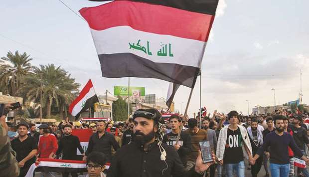 Iraqi protesters march with a national flag during an anti-government demonstration in the southern city of Basra, yesterday.