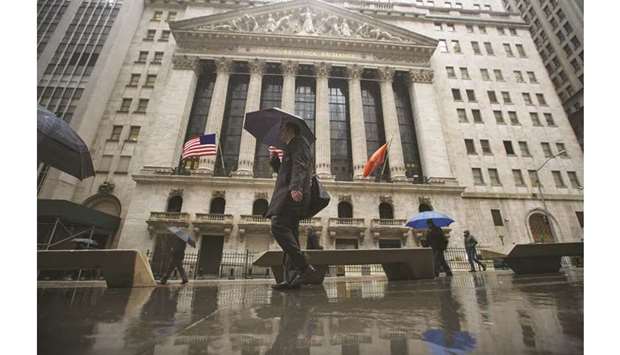 Pedestrians walk past the New York Stock Exchange. Even though the US stock market continues a record-breaking rally that has sent the benchmark S&P 500 index up nearly 25% for the year, investors appear to be looking elsewhere for better values in the year ahead.