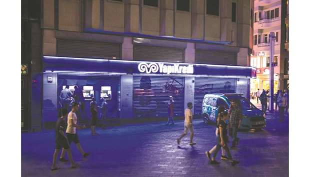 Customers use automated teller machines illuminated at night outside a Yapi ve Kredi Bankasi bank branch on Taksim Square in Istanbul (file). UniCredit will exit the special purpose vehicle through which it and Turkish industrial group Koc hold a combined stake of over 80% stake in the bank, it said in a statement yesterday.