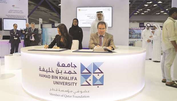Dr Mounir Hamdi and Lana Khalaf signing the pact at the HBKU booth.