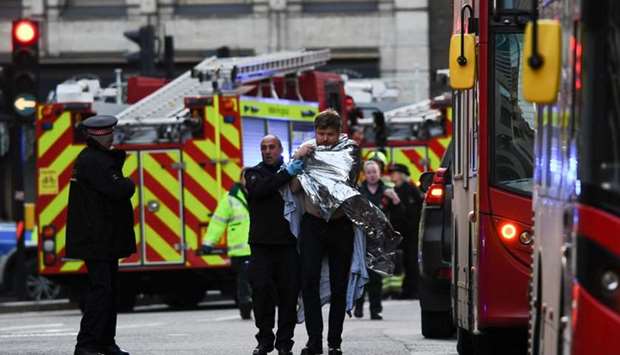 Police assist an injured man near London Bridge in London yesterday after reports of shots being fired on London Bridge