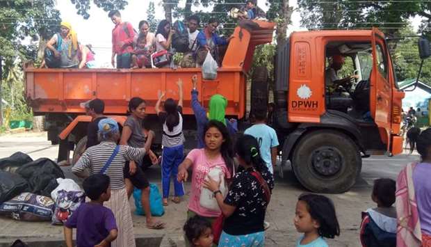 Residents, whose village were affected by a landslide due to a 6.5-magnitude earthquake, disembark from a government truck at a school compound in Makalila town, north Cotabato province, on November 1