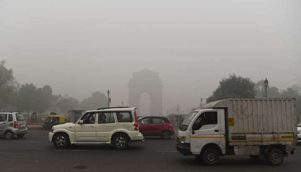 Motorists drive along a road under heavy smog conditions near India Gate