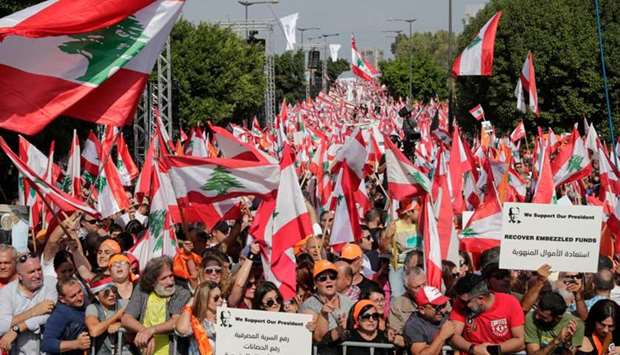 Supporters of Lebanese President Michel Aoun wave national flags and orange-coloured banners of the political party he founded (Free Patriotic Movement) during a counter-protest near the presidential palace in Baabda