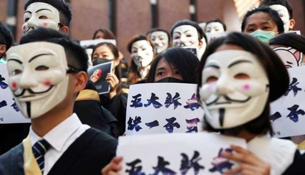 University students wearing Guy Fawkes masks pose during a news conference to support anti-government protests before their graduation ceremony at the Hong Kong Polytechnic University in Hong Kong,