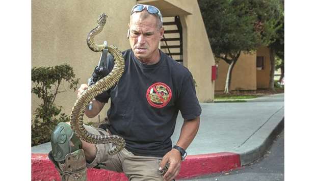 EXPERT: Rattlesnake wrangler Bo Slyapich transfers a rattlesnake from one plastic container into a larger one after catching it the night before, when he responded to an emergency call from a homeowner in Hidden Hills, California.