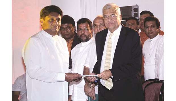 Sajith Premadasa, left, Sri Lankau2019s housing minister and the presidential candidate of the ruling United National Party (UNP)-led New Democratic Front alliance, hands over a copy of his election manifesto to Prime Minister Ranil Wickremesinghe during the election manifesto launching ceremony, in Kandy yesterday.