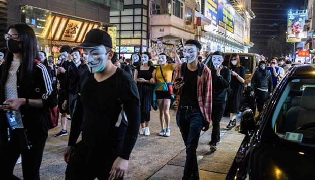 Protesters wearing a Guy Fawkes mask - after the British Catholic rebel who attempted to blow up parliament in the fifteenth century - walk in the Kowloon district of Hong Kong yesterday
