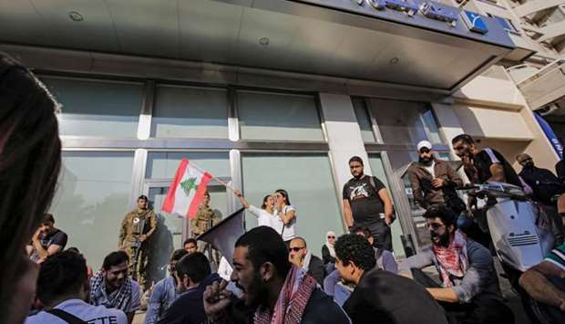 Members of the Lebanese Armed Forces stand guard as anti-government protesters shout slogans while attempting to shut down the local branch of the Banque du Liban (Lebanese Central Bank) in the northern port city of Tripoli