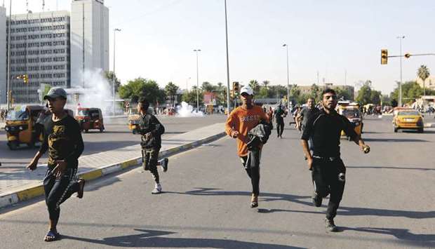 Demonstrators run after Iraqi security forces fired tear gas during the ongoing anti-government protests in Baghdad, yesterday.
