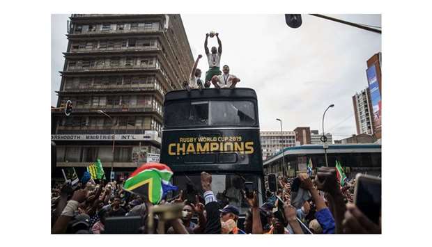 South African captain Siya Kolisi (centre) holds up the Web Ellis trophy as the World Cup champions parade through the streets of Johannesburg on an open top bus yesterday. (AFP)