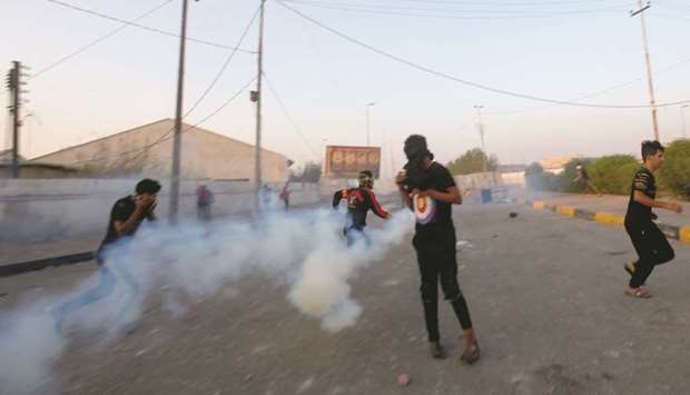 Demonstrators run away from tear gas during the ongoing anti-government protests near the Governorate building of Basra, yesterday.
