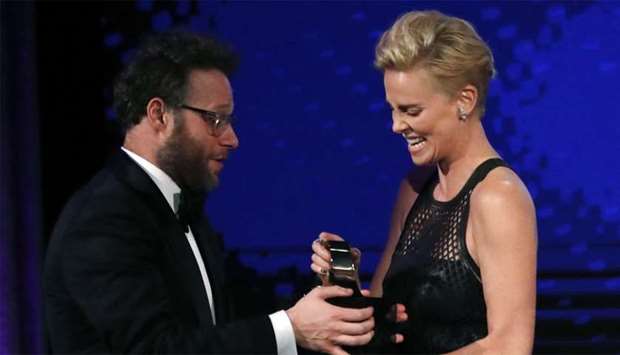 Charlize Theron accepts her award from presenter Seth Rogen.