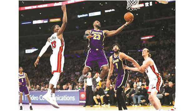 LeBron James (second from left) of the LA Lakers drives past Bam Adebayo (left) of the Miami Heat for a layup during the second half of a NBA game at Staples Center in Los Angeles, United States, on Friday. (AFP)