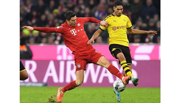 Bayern Munichu2019s Robert Lewandowski (left) and Dortmundu2019s Achraf Hakimi vie for the ball. (AFP)