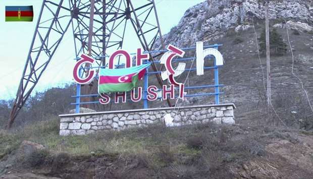 An Azeri flag hanging on a sign reading Shushi in Russian and Armenian (Shusha in Azerbaijani) on the side of a road entering the town of Shushi (Shusha) in the breakaway region of Nagorno-Karabakh. Image grab taken from a video made available on the official web site of the Azerbaijani Defence Ministry.