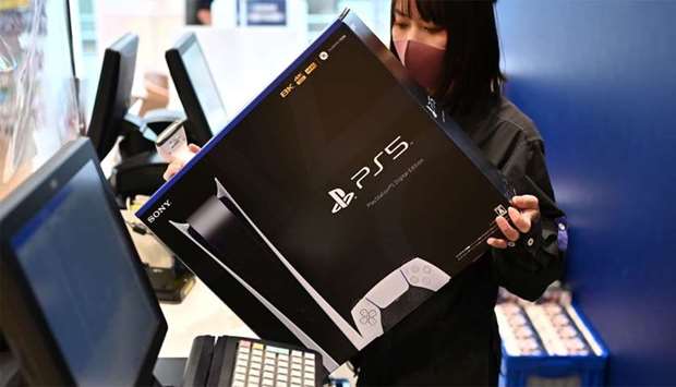 An employee prepares the new Sony PlayStation 5 gaming console for a customer on the first day of its launch, at an electronics shop in Kawasaki
