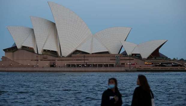 (File photo) People stand on the harbour waterfront near the Sydney Opera House in Sydney, Australia.