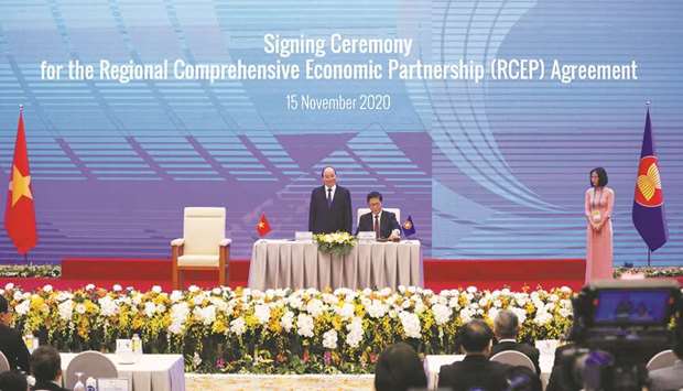 Vietnamu2019s Industry and Trade Minister Tran Tuan Anh (centre) signs as Vietnamu2019s Prime Minister Nguyen Xuan Phuc (left) witnesses during the signing ceremony of the Regional Comprehensive Economic Partnership (RCEP) Agreement during the 37th Asean summit in Hanoi, Vietnam yesterday.