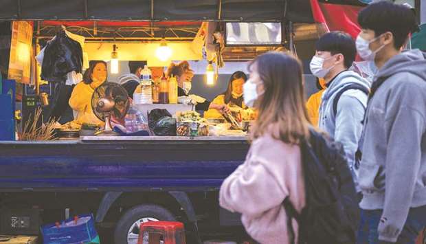 People wearing face masks walk past a food stall on a street in Seoul yesterday.