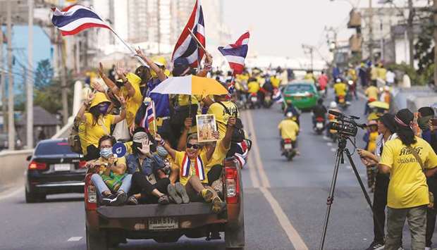 Royalists hold national flags while riding towards a rally in front of the parliament, to show their opposition towards the proposed motion to amend the Constitution on articles related to the monarchy, in Bangkok.